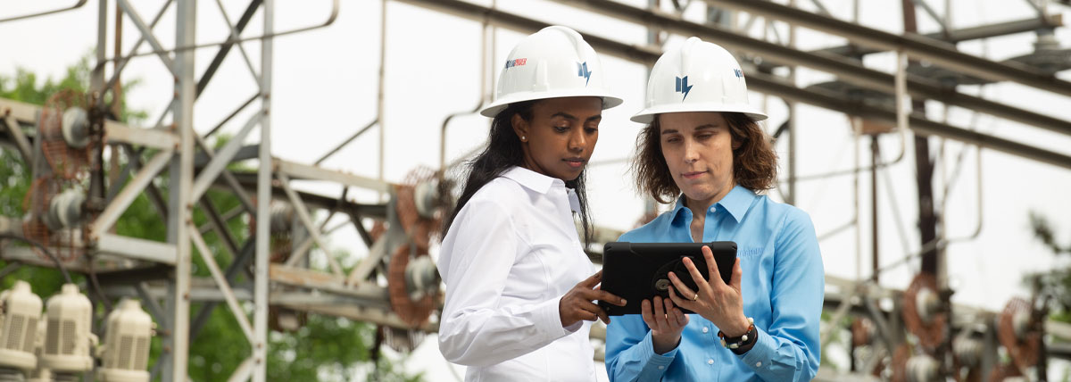 women working with tablet at power grid outdoors