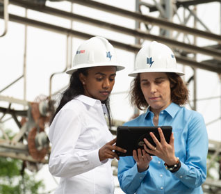 women working with tablet at power grid outdoors